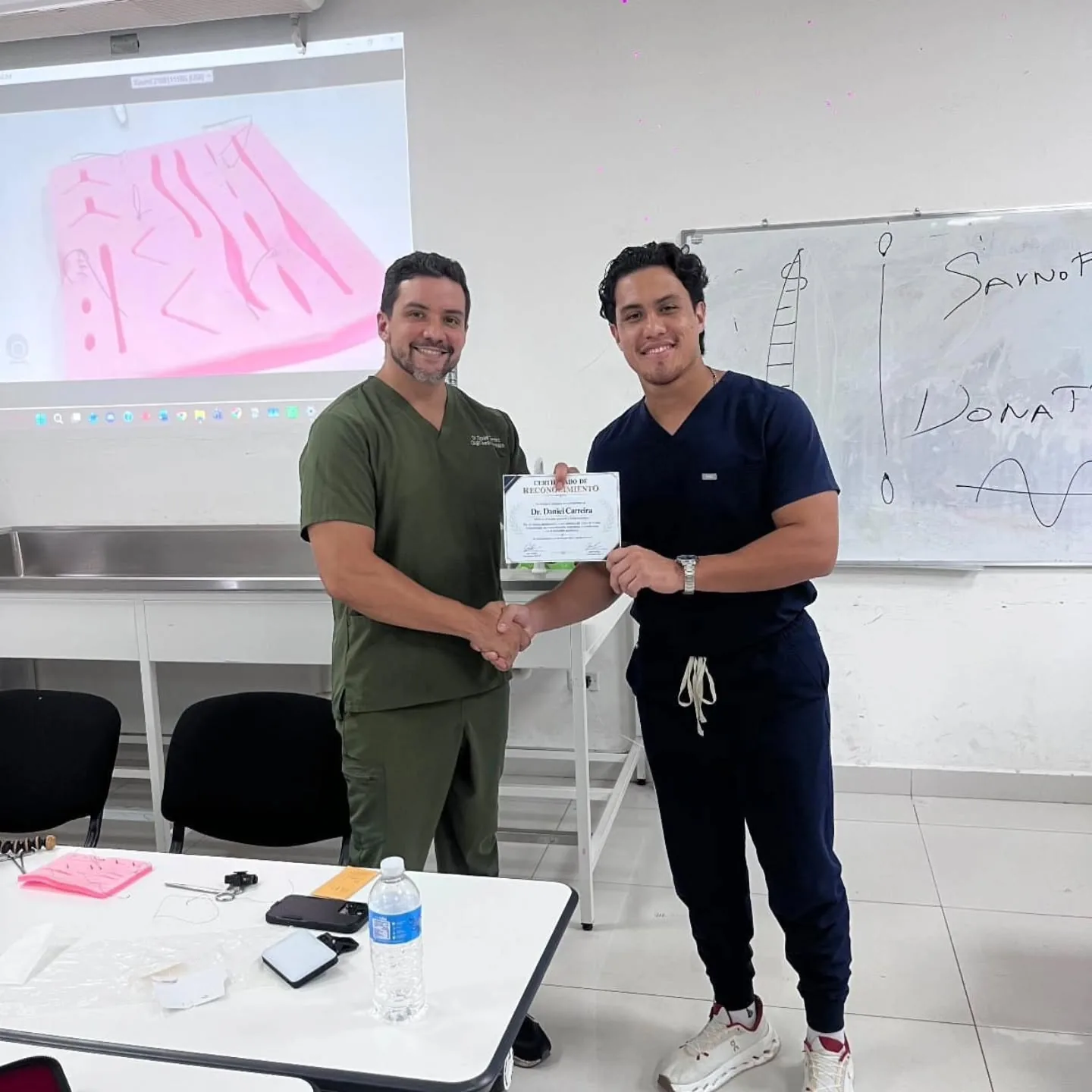 El Dr. Carreira entrega un certificado del taller de suturas